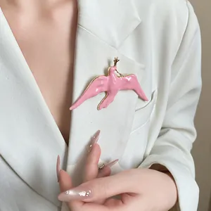 Elegant pink enamel swallow bird brooch detail pinned on a white blazer jacket.