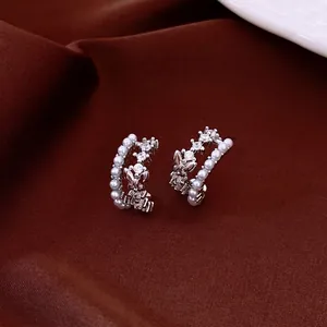 Elegant silver C-shaped earrings with pearls and butterfly motif on burgundy velvet