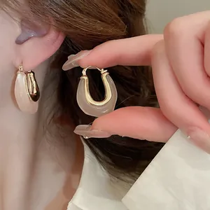 Close-up of U-shaped jelly resin earrings with gold metal inlay and minimalist design