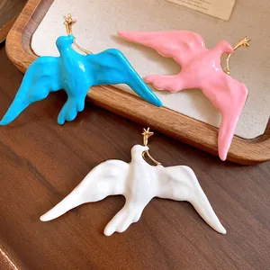 Detail view showing glossy enamel finish and gold star accent of swallow brooches