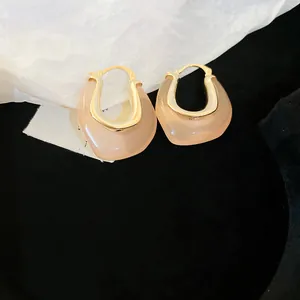 Close-up of elegant U-shaped jelly resin hoop earrings with premium gold finish