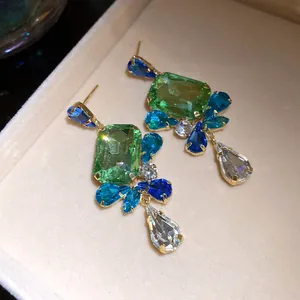 Close-up of vintage earrings with square green crystals and blue pear-shaped drops.