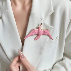 Elegant pink enamel swallow brooch pinned on a white blazer detail