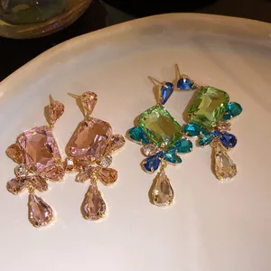 Close-up of vintage square pendant earrings in pink and green crystal variants.