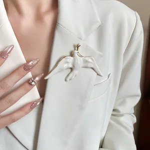 Detailed view of an elegant white enamel bird brooch on a stylish blazer lapel