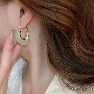 Close-up of elegant U-shaped light green jelly resin hoop earrings on model's ear