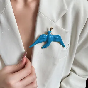 Close-up detail of a vintage blue enamel swallow bird brooch pinned on a white blazer