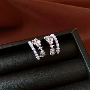 Exquisite close-up of butterfly C-shaped stud earrings featuring pearls and sparkling zircons