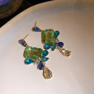Detailed view of luxury vintage-style square green and blue gemstone earrings with clear teardrop charm