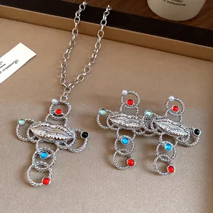Detailed view of retro silver cross necklace and earrings set with pearls and lip design