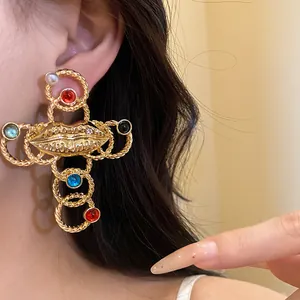 Detailed close-up of a vintage gold lip cross earring with colorful gems and pearls