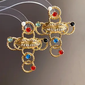 Close-up of vintage gold cross necklace featuring central lip motif and colorful resin gems