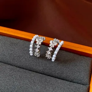 Detailed view of elegant C-shaped silver earrings featuring butterflies, zircons and pearls