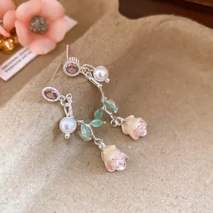 Close-up of elegant floral dangle earrings with pink zircon, pearls and rosebuds.