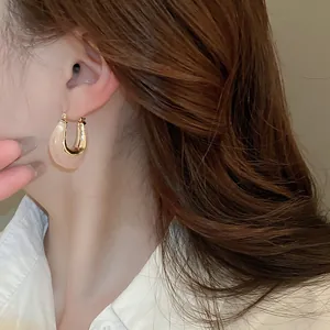 Detail shot of a model wearing U-shaped jelly resin earrings in a golden finish.