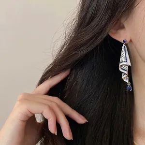 Eleganti orecchini a pendente con pietre blu indossati da una modella, dettaglio.