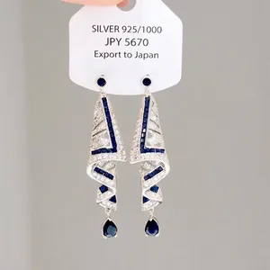 Primo piano di eleganti orecchini a goccia in argento con gocce di zaffiro blu scintillanti.