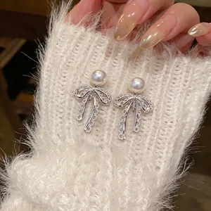 Elegant lace bow pearl earrings for non-pierced ears shown on white sweater