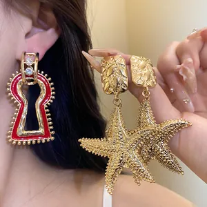 Close-up of vintage red keyhole drop earring and textured gold starfish pendants