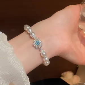 Nahaufnahme eines eleganten französischen Perlenarmbands mit herzförmigem blauem Edelstein