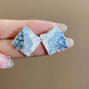 Dettaglio ravvicinato di orecchini a lobo geometrici in vetro blu con texture fine