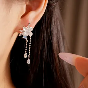 Dettaglio di eleganti orecchini a nappa a fiore in argento con zirconi indossati