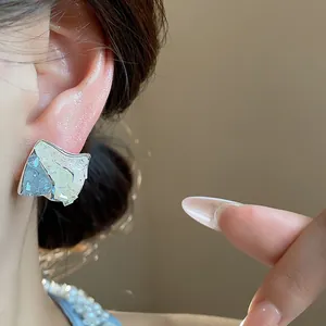 Dettaglio ravvicinato di orecchini geometrici in vetro con ago in argento e design di nicchia
