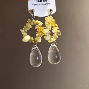 Macro di orecchini vintage con pietre gialle grezze e pendenti trasparenti a goccia d'acqua
