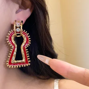 Close-up detail view of vintage red enamel earrings with shiny rhinestones on ear.