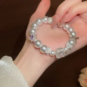 Detailansicht eines Perlenarmbands mit quadratischem Kristall und Schleife.