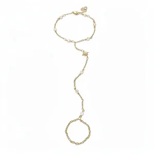 Elegant gold plated slave bracelet with star charm and white pearls on white background