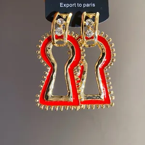Close-up of vintage red enamel keyhole drop earrings with gold-plated finish and rhinestones