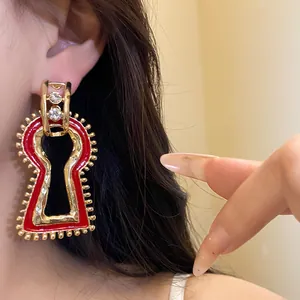 Close-up detail of retro red enamel keyhole earrings with rhinestones worn on ear