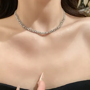 Close-up of elegant silver necklace with sparkling square rhinestones on skin.