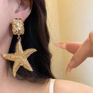 Detailed close-up of a large vintage gold starfish drop earring worn by an Asian model