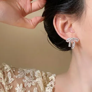 Detailed view of a sweet lace bow clip-on earring worn on the earlobe in a close-up shot.