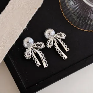 Detailed shot of silver lace bow clip-on earrings with mosquito coil backs for non-pierced ears