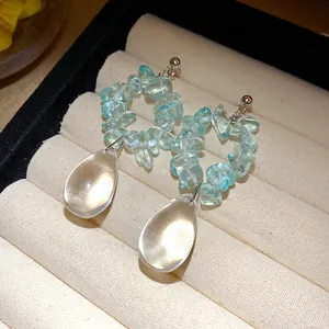 Dettaglio di orecchini vintage con pietre blu irregolari e pendenti a goccia trasparenti.