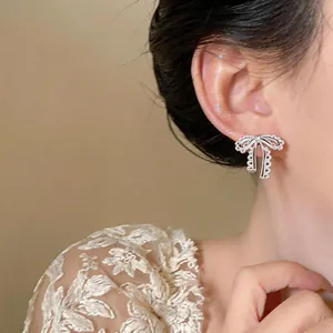 Detailed close-up view of elegant silver lace bow clip-on earrings worn by a model