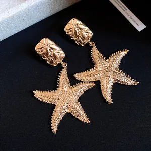Detailed shot of textured gold starfish dangle earrings in retro style