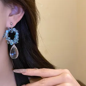 Dettaglio di orecchini vintage con pietre blu e ciondolo a goccia d'acqua