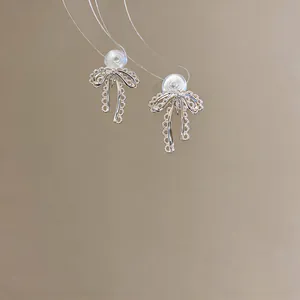 Close-up detail of elegant silver lace bowknot clip-on earrings on a neutral background
