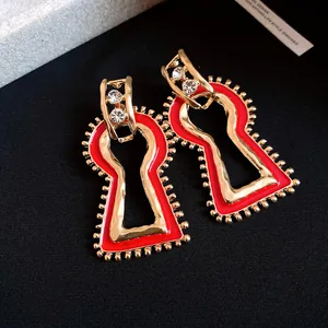 Detailed view of vintage gold-toned geometric dangle earrings with red enamel and crystals