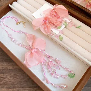 Collier à perles roses avec fleurs en tissu et pompons au style forêt douce et chic