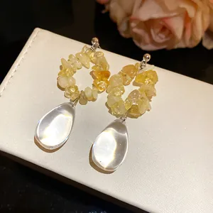 Dettaglio di orecchini vintage con pietre naturali gialle e pendenti a forma di goccia d'acqua