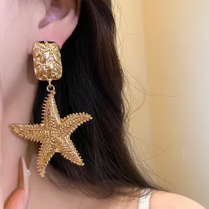 Detailed macro view of vintage gold starfish dangle earrings worn by a female model.