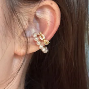 Detailed close-up showing elegant pearl and gold crystal non-pierced ear cuffs on a person's ear