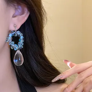 Dettaglio di orecchini vintage con pietre blu e un pendente a goccia d'acqua.