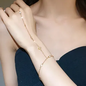 Detail of a dainty gold chain ring-bracelet with zircon star accents on an Asian model