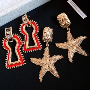 Detail of vintage gold starfish and red enamel keyhole drop earrings with studs
